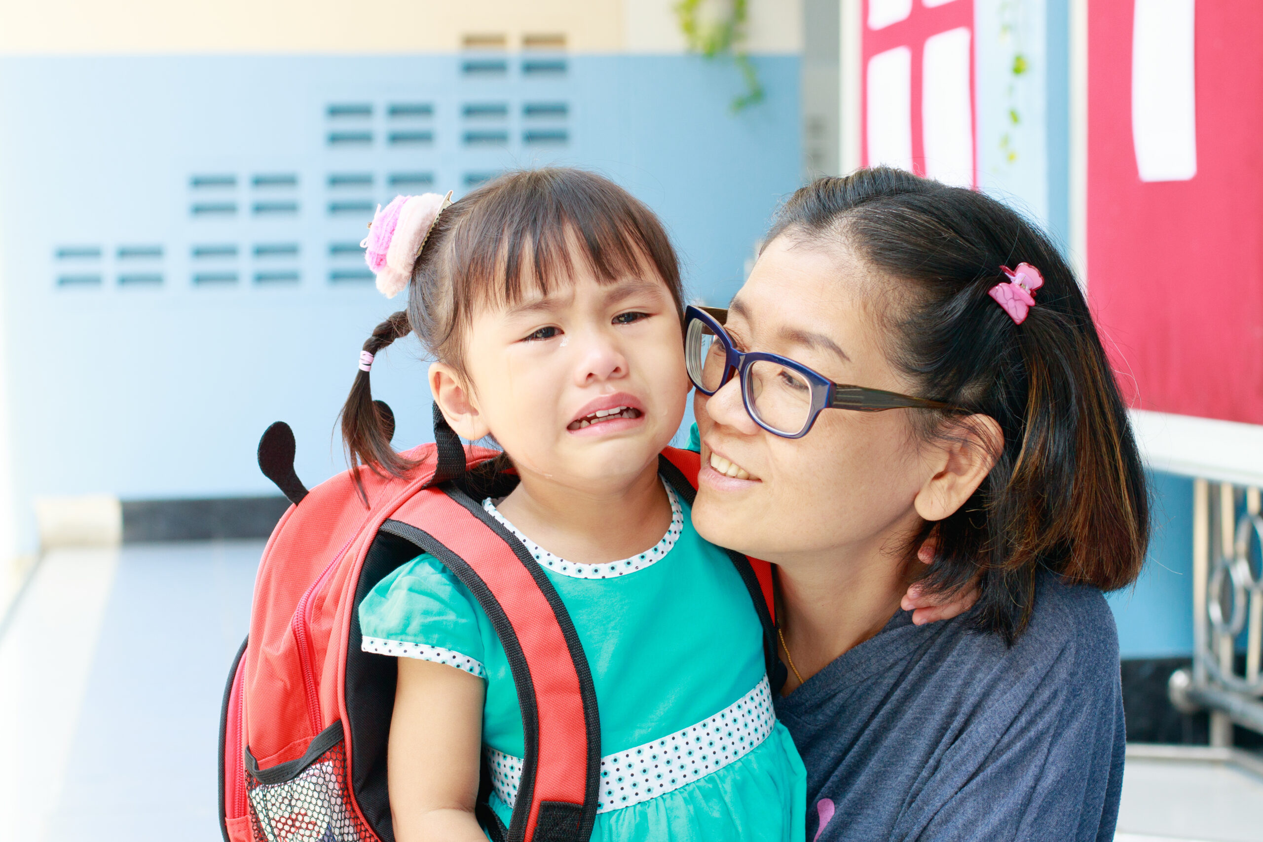 A woman stands closely to a crying child.