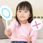 A young girl holds two props that designate her choice.