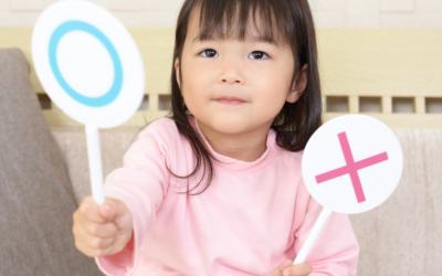 A young girl holds two props that designate her choice.