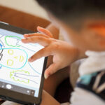 A young boy draws a picture using a tablet.